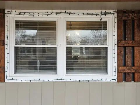 Pair of new white windows with brown shutters on a brick Tulsa home