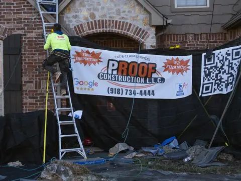 Proof Construction crew working beside a brick chimney under a job banner