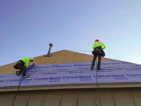 Roofer setting synthetic underlayment