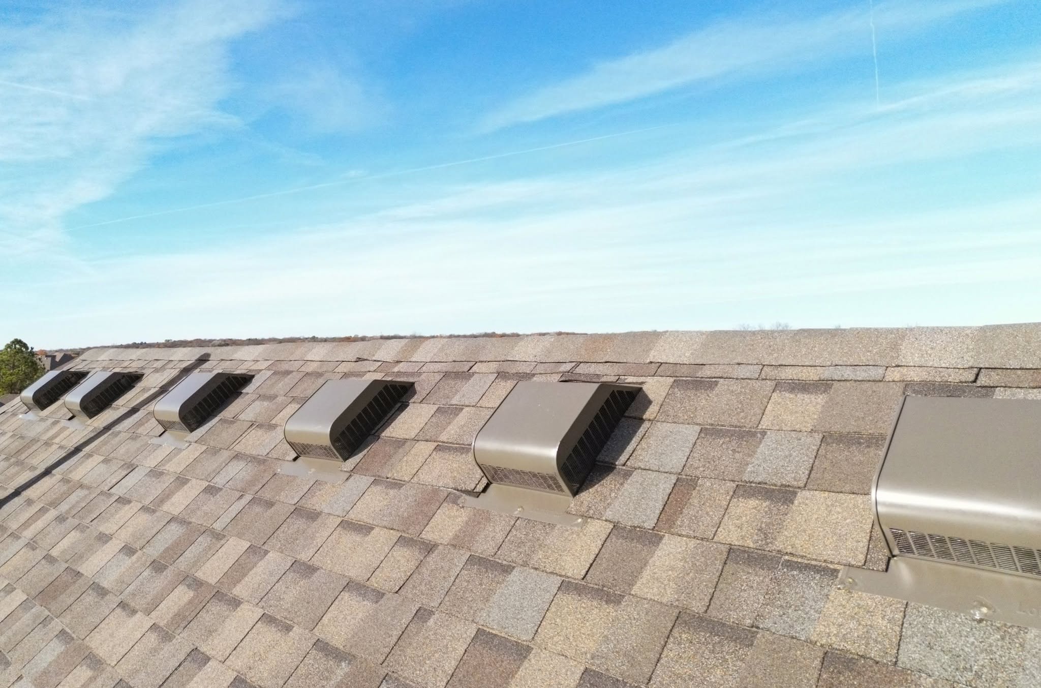 A rooftop with multiple vents under a bright blue sky.
