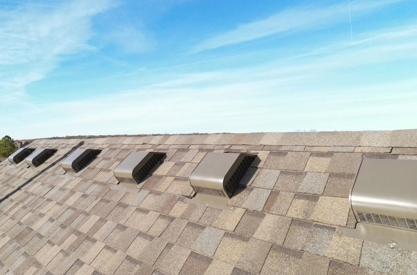 A rooftop with multiple vents under a bright blue sky.