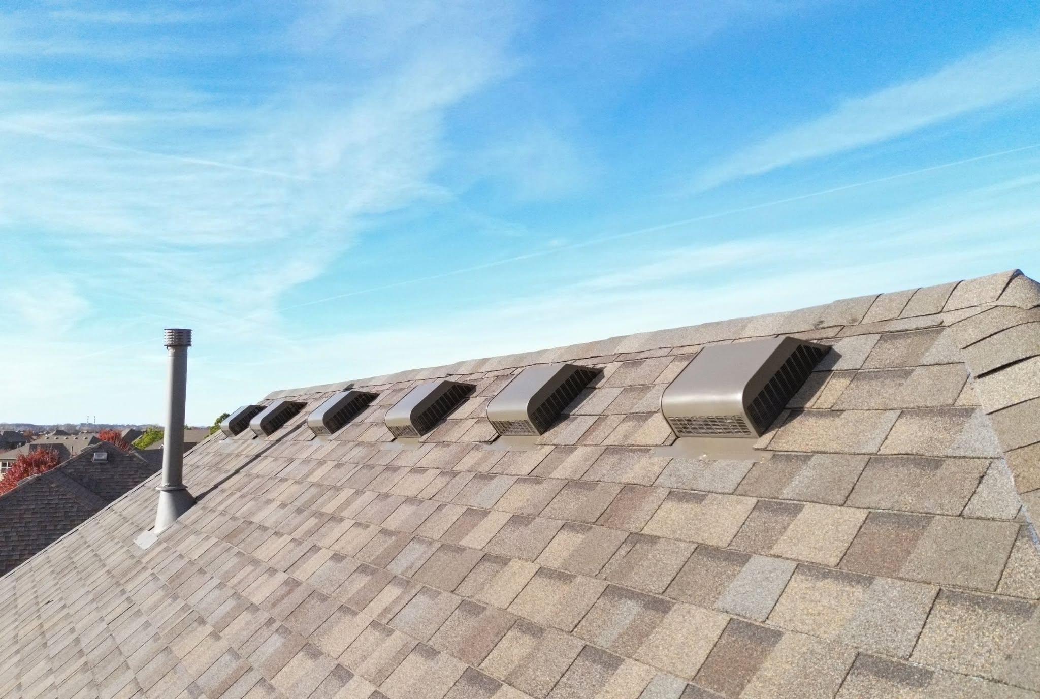 A rooftop with vents and a chimney under a blue sky.