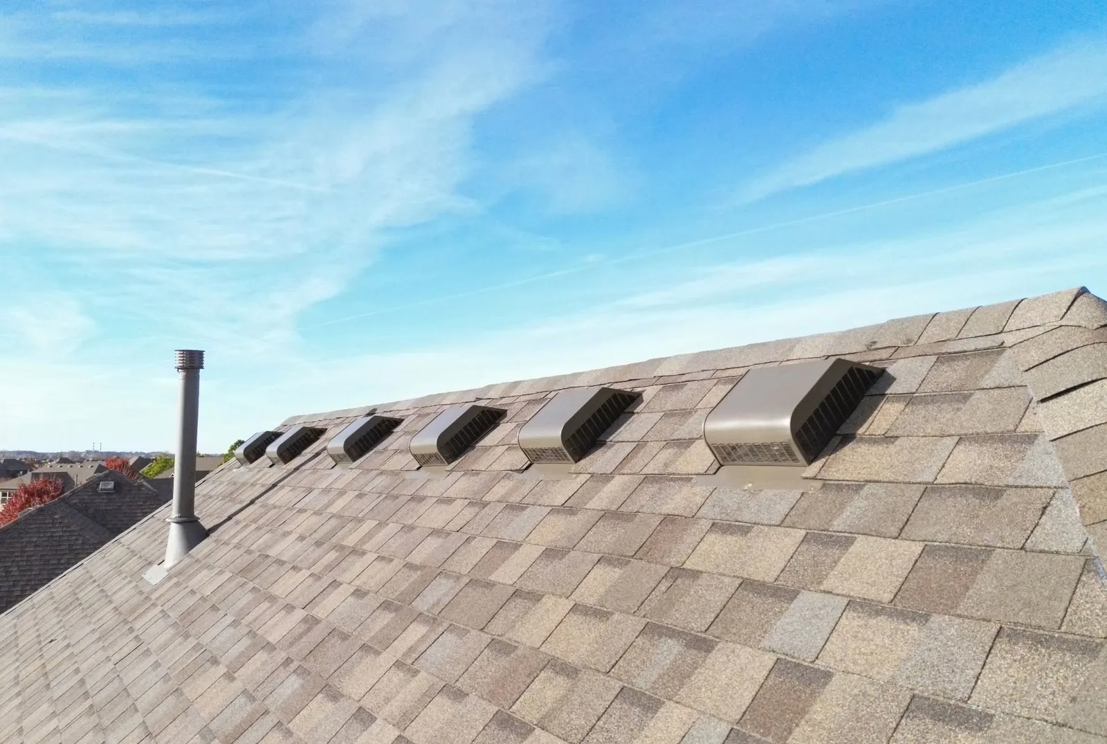 A rooftop with vents and a chimney under a blue sky.