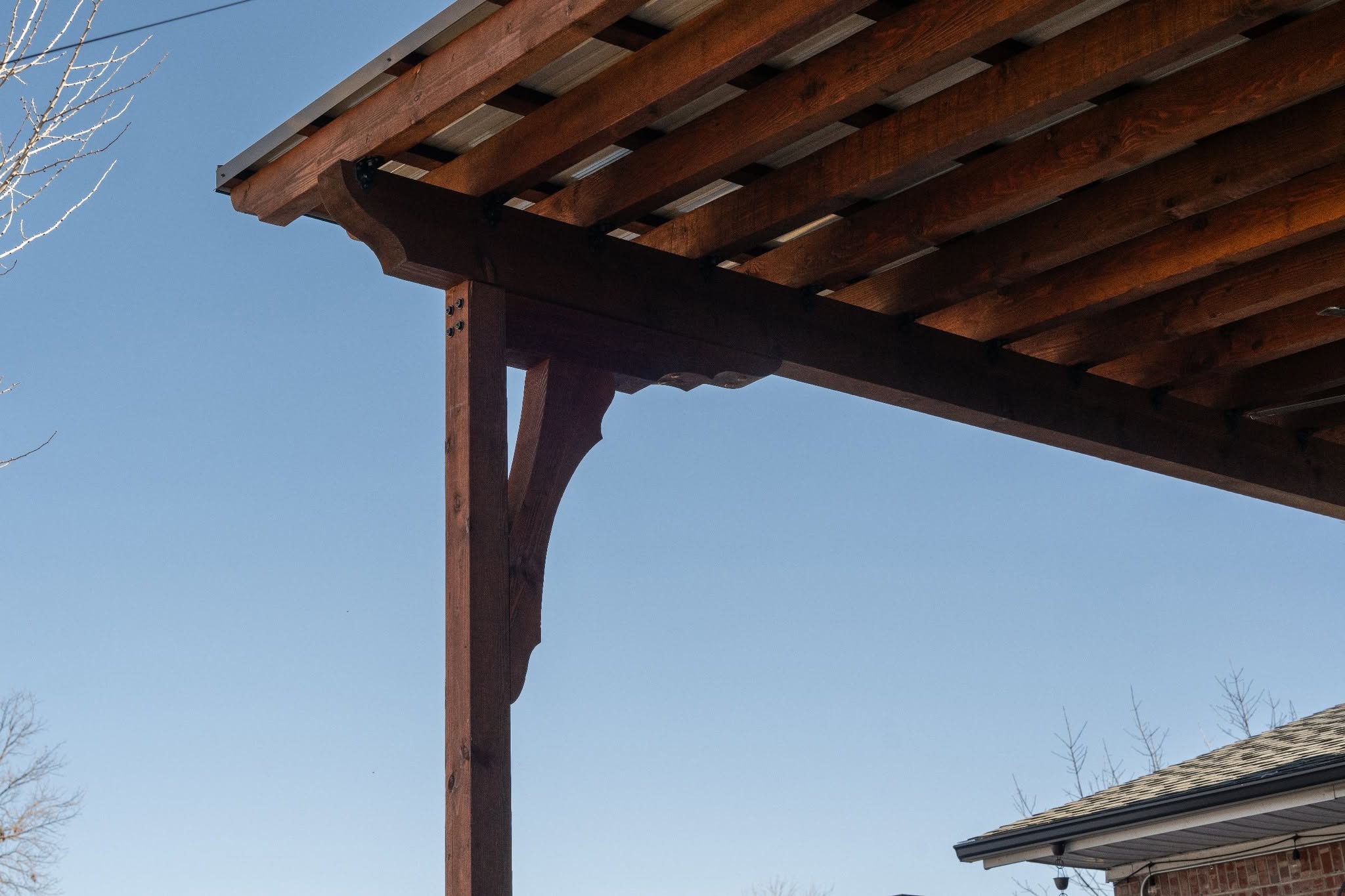 A wooden pergola is shown against a clear blue sky.