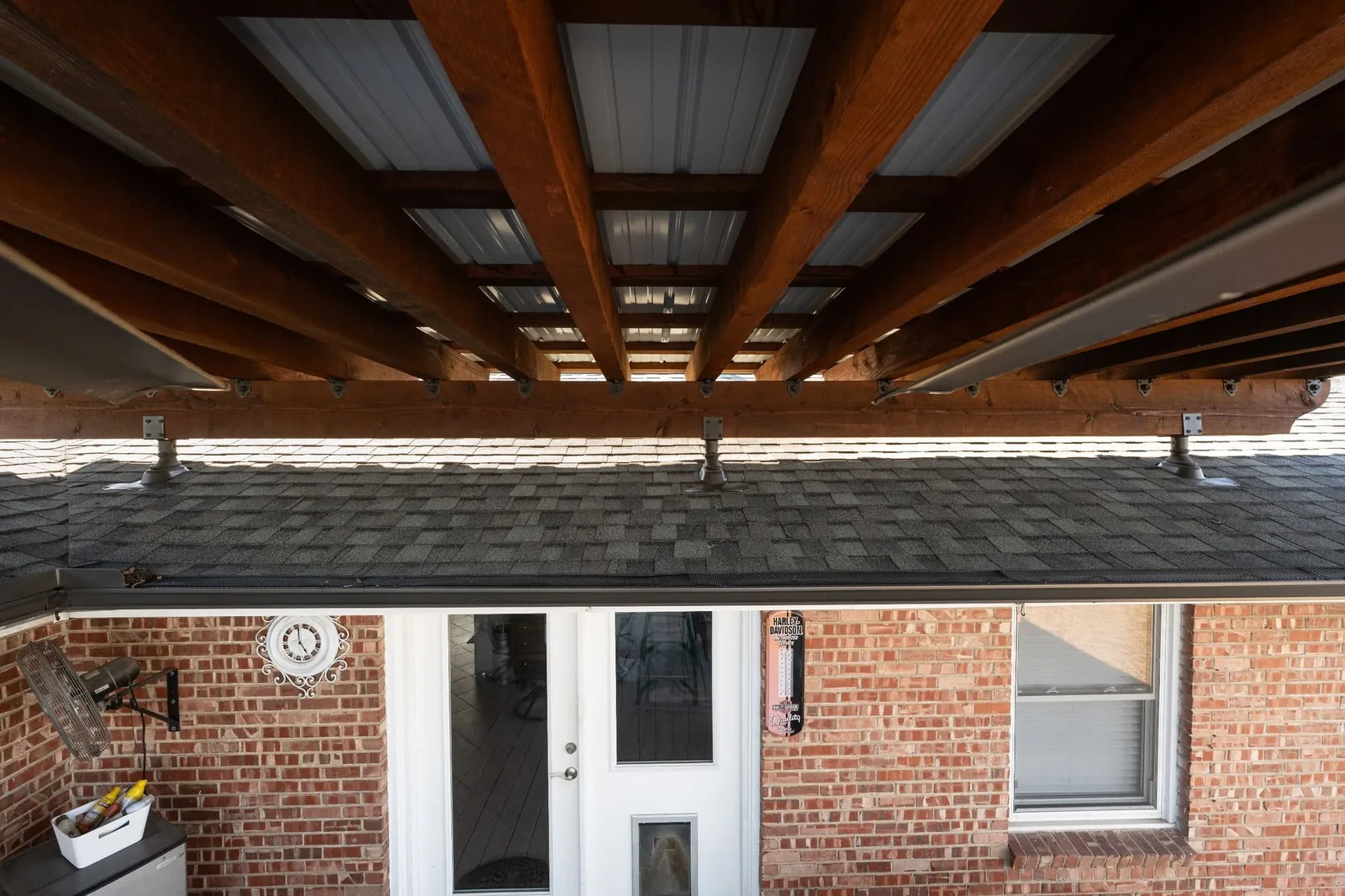 A covered patio with a brick wall, doors, and a window.