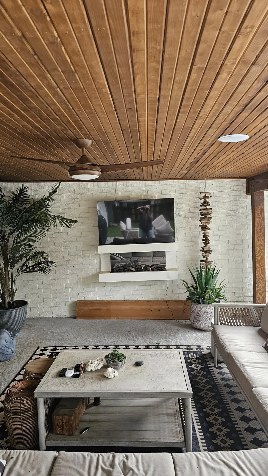 A modern outdoor living space with a TV, fireplace, and seating.