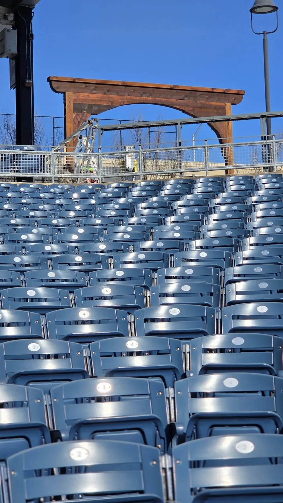 Empty blue stadium seats are shown in front of a wooden archway.