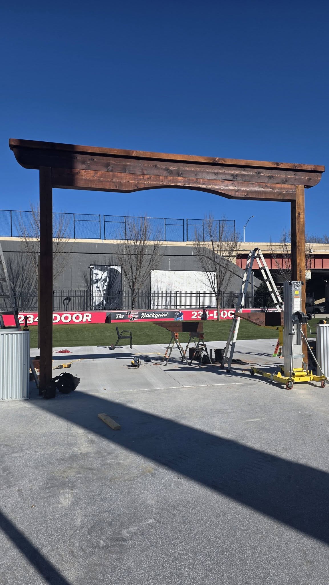 A wooden archway is being constructed outdoors in front of a building with a large mural.