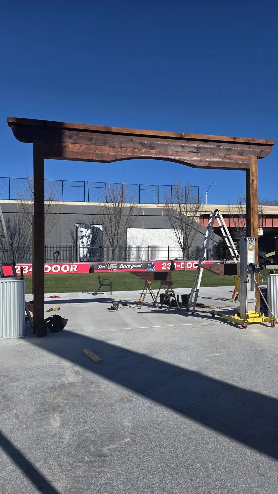 A wooden archway is being constructed outdoors in front of a building with a large mural.