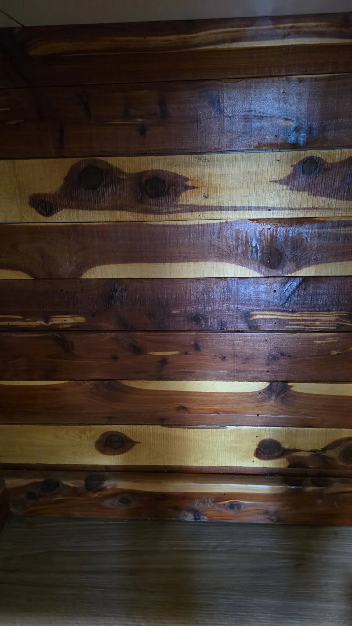 A close-up shot of a wooden wall with alternating dark and light planks.