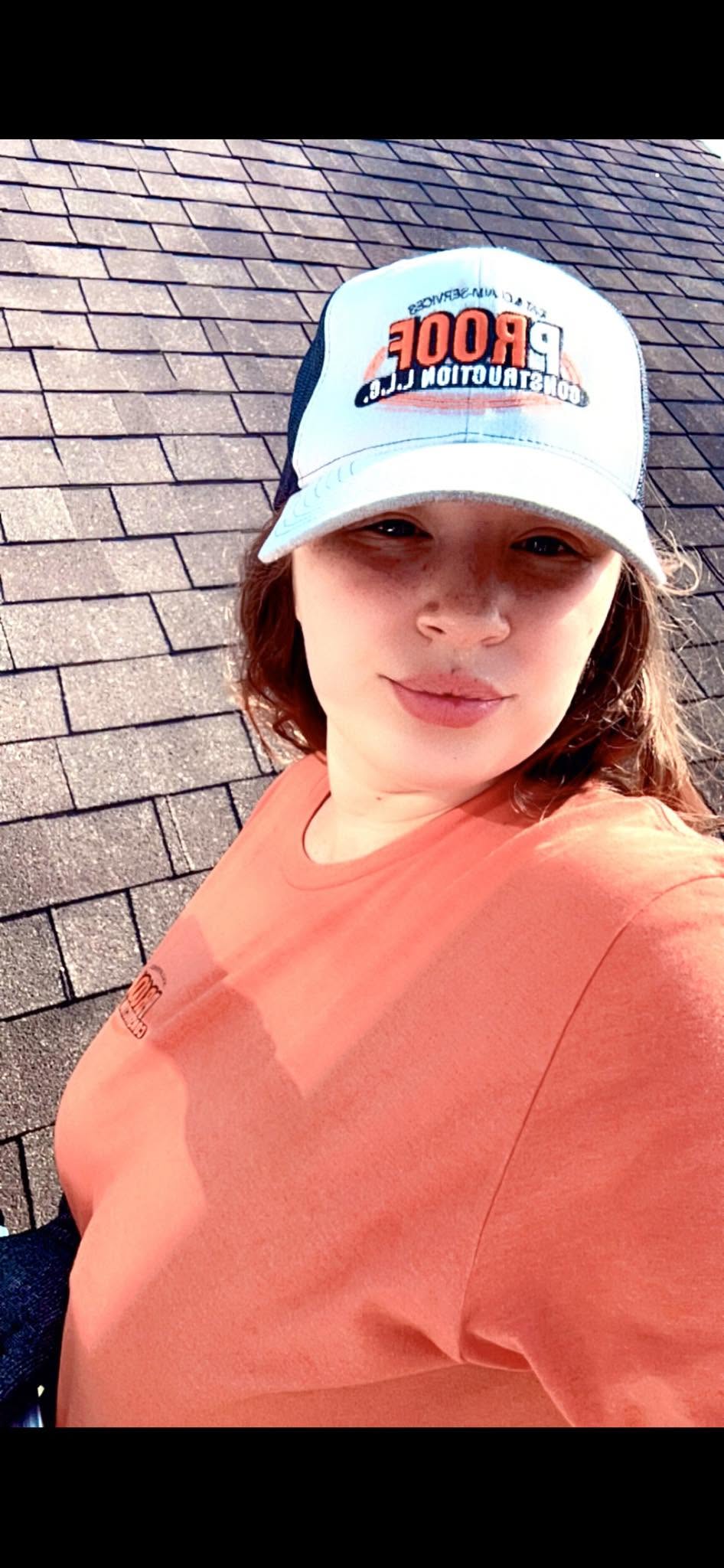 A person wearing a hat and orange shirt is on a roof.