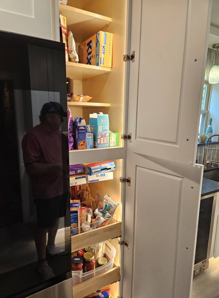 A man stands in a pantry filled with food and shelves.