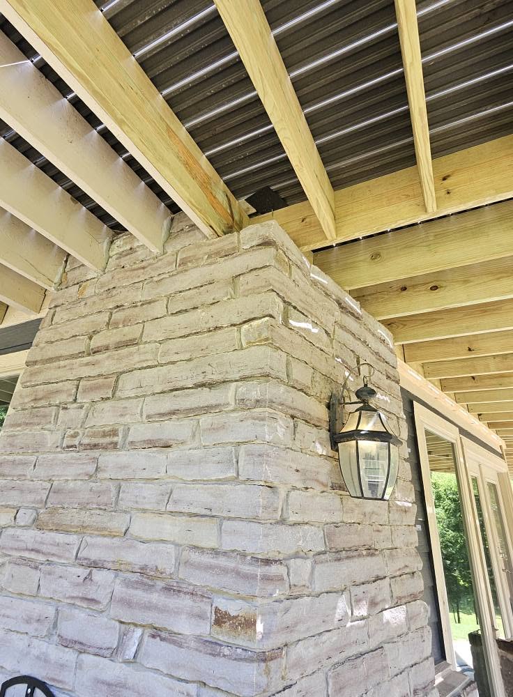 A stone pillar with a lantern is shown under a wooden roof.